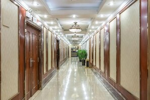 A hotel corridor with wooden doors, recessed lighting, and a plant. - Zhoukou Hotel (Zhoukou Wanshunda Department Store) (Zhoukou)