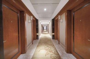 Un pasillo de hotel con puertas de madera, alfombra estampada y una lámpara en el techo.