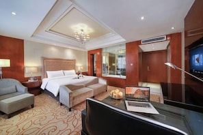 Una habitación de hotel con cama, escritorio, silla y televisor.