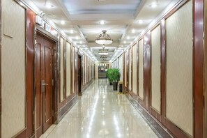 A long, well-lit hallway with wooden doors and a central plant. - Zhoukou Hotel (Zhoukou Wanshunda Department Store) (Zhoukou)