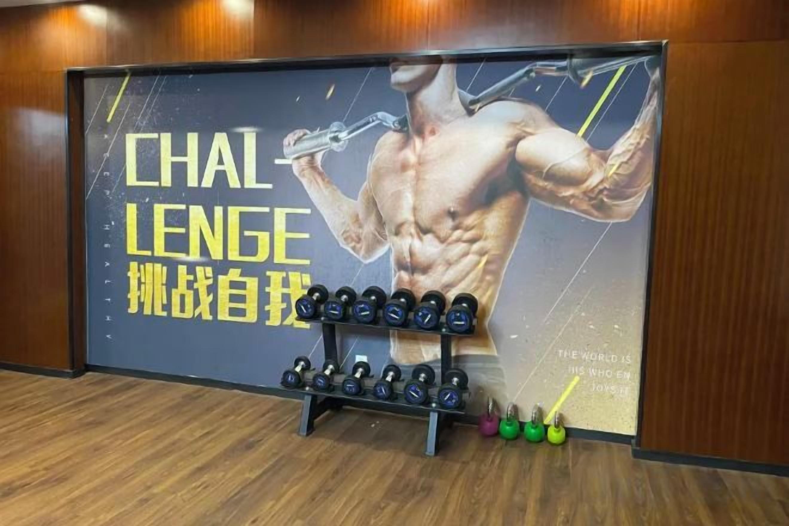 Et fitnessrum med en stor plakat, håndvægte og kettlebells.