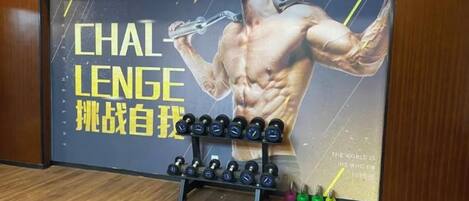 Et fitnessrum med en stor plakat, håndvægte og kettlebells.
