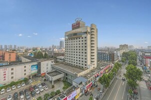 Un hotel de varios pisos con una ubicación destacada en una esquina, estacionamiento y vistas a la ciudad.