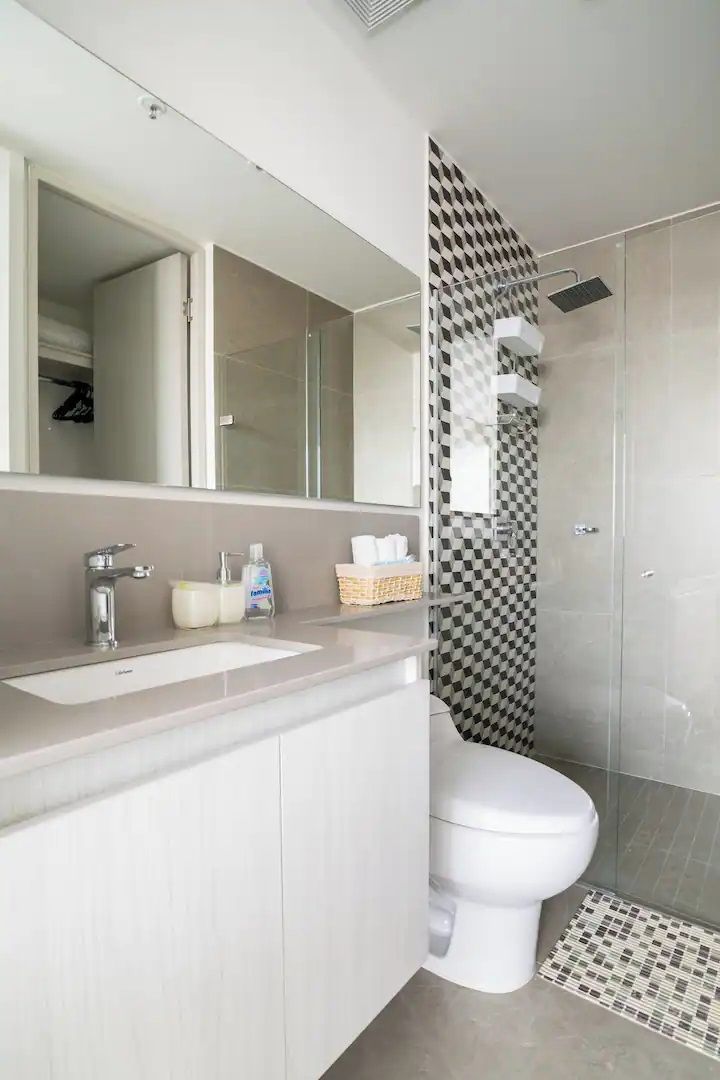 A modern bathroom with a white sink, mirror, and toilet.