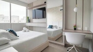 A modern hotel room with a large bed, a desk, and a TV mounted on the wall. - Distrito 90 By Hostpro (Barranquilla)