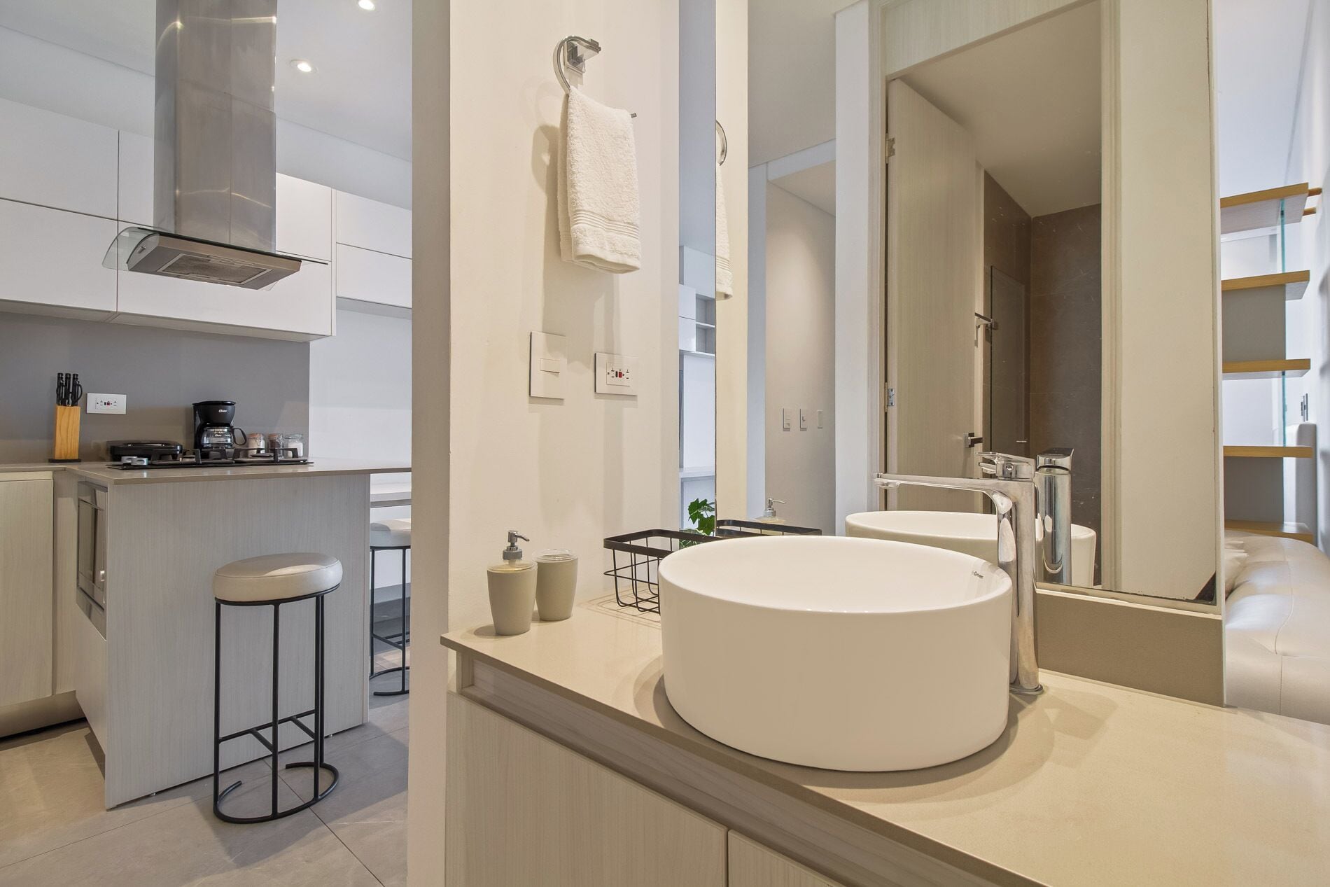 A modern bathroom with a large mirror, a round sink, and a shower area.