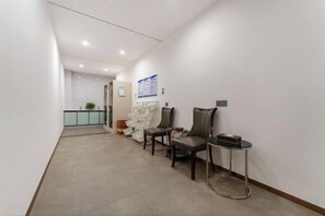 A hallway with a reception desk, two chairs, and a small table. - Antai Hotel (Maoming)