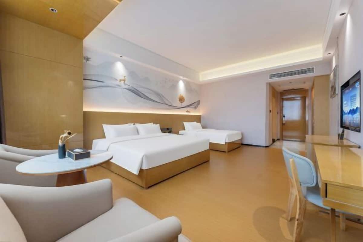 A hotel room with two beds, a desk, a chair, and a TV.