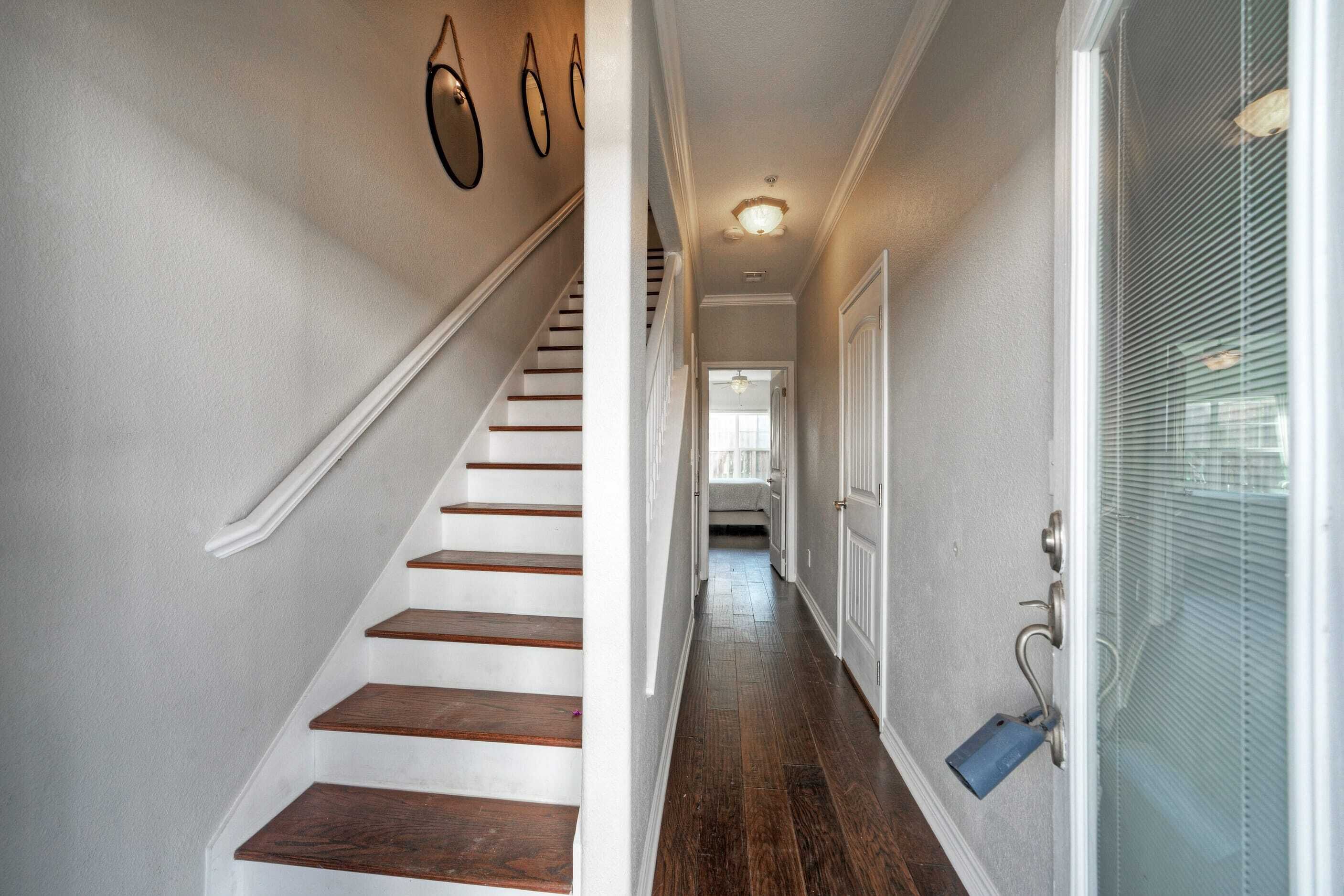 Eine Treppe führt zu einer zweiten Etage mit Holzausstattung und weißen Wänden.