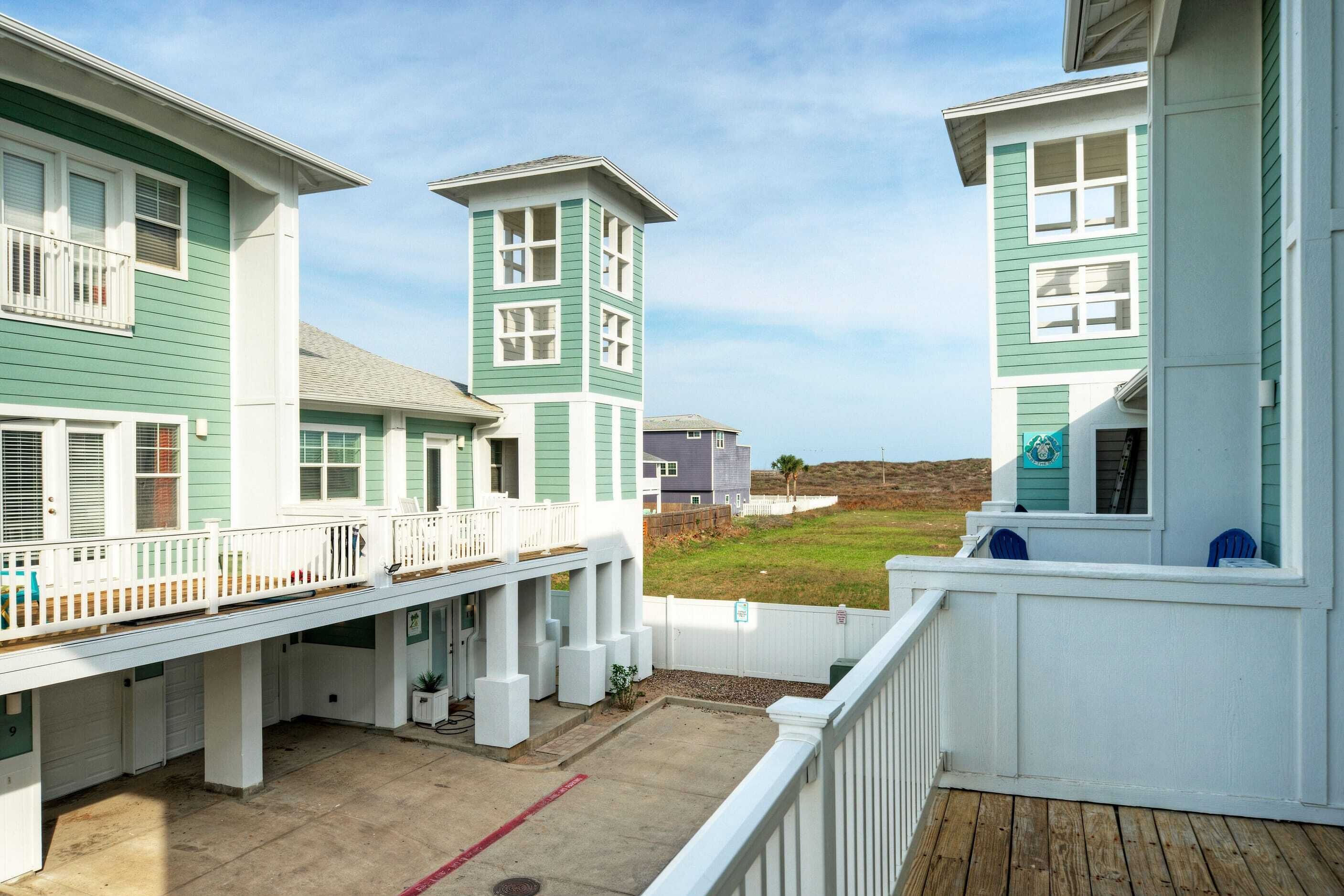Ein Küstengebäude mit Balkon, Turm und Blick auf den Strand.