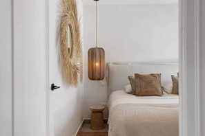 A bedroom with a bed, pillows, a hanging light fixture, and a wall-mounted decor piece. - Villa Violeta Estepona Old Town (Estepona)