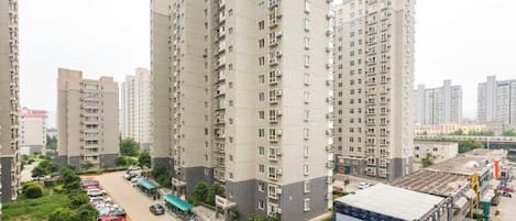 Un edificio residencial de gran altura con varios balcones, un estacionamiento y una estructura con techo azul.