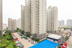 Edifício residencial alto com várias sacadas, área de estacionamento e estrutura com telhado azul.