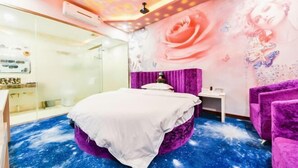 Une chambre à coucher avec un lit, une coiffeuse, un fauteuil violet et un mur décoré de motifs de roses et de papillons.
