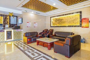 A hotel lobby with a reception desk, seating area, and a large wall mural.