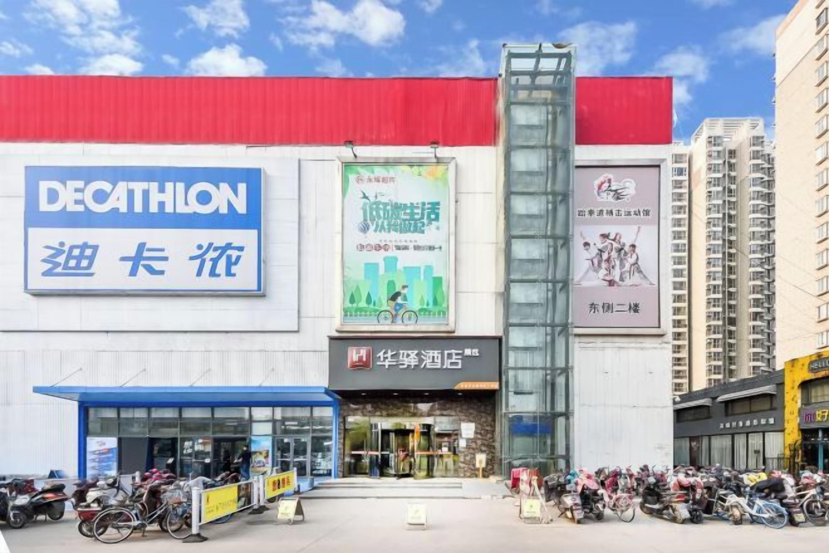 Un bâtiment avec une grande enseigne bleue sur laquelle on peut lire « DECATHLON » et une plus petite enseigne avec des caractères chinois. Plusieurs motos sont garées devant.