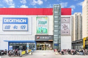 Een gebouw met een groot blauw bord waarop 'DECATHLON' staat en een kleiner bord met Chinese karakters. Er staan verschillende motorfietsen voor geparkeerd.