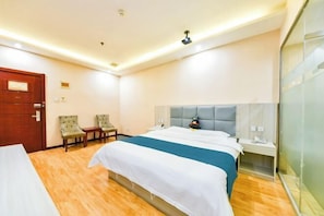 A hotel room with a large bed, two chairs, a bedside table, and a glass partition wall. - Huayi Hotel(Shijiazhuang Huai'an East Road) (Shijiazhuang)