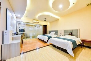 Two beds with white bedding, a desk, and a wall-mounted TV make this room a comfortable retreat.