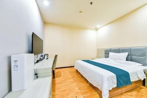 A hotel room with a bed, a desk, a chair, a flat-screen TV, and a small refrigerator. - Huayi Hotel(Shijiazhuang Huai'an East Road) (Shijiazhuang)