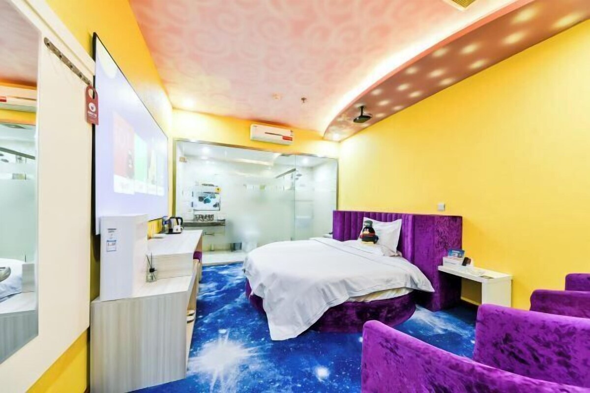 A hotel room with a bed, a desk, a chair, and a ceiling with a floral pattern.