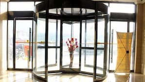 Une porte tournante avec des panneaux de verre et un vase de fleurs au centre.