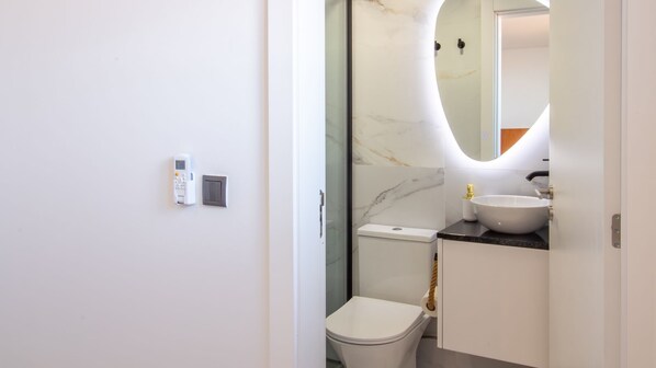A modern bathroom with a toilet, sink, and a glass-enclosed shower area. - Quiet Duplex w/ Patio in Lapa by LovelyStay (Porto)