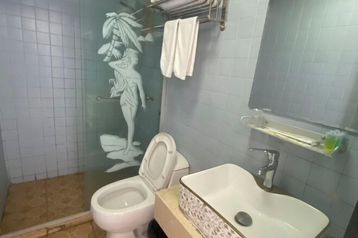 A bathroom with a toilet, sink, and a glass shower enclosure.
