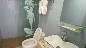 A bathroom with a toilet, sink, and a glass shower enclosure.