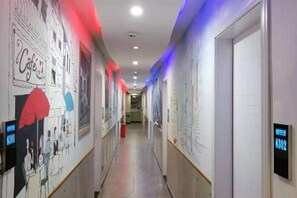 Un couloir d’hôtel agrémenté d’œuvres d’art aux murs, de panneaux d’affichage numériques et doté d’un design épuré et moderne.