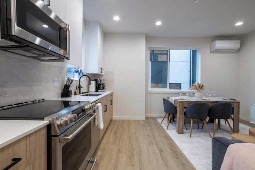 A modern kitchen with a built-in oven, microwave, and stove. There is a dining area with a table and chairs.