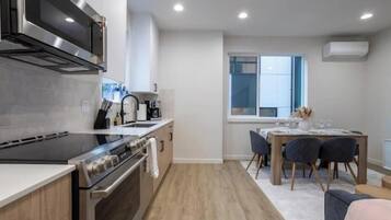 A modern kitchen with a built-in oven, microwave, and stove. There is a dining area with a table and chairs.