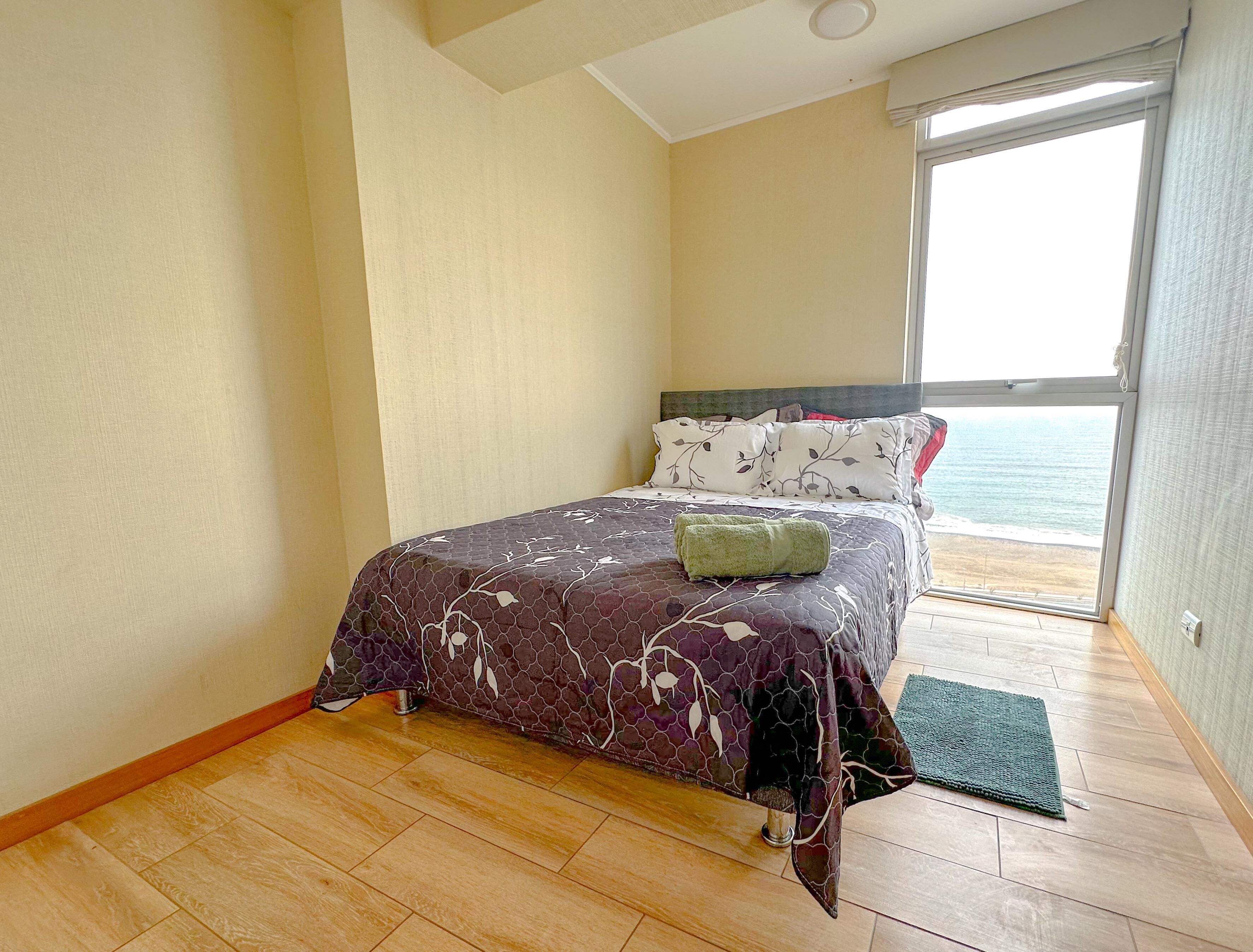 A bedroom with a bed, a view of the sea, and a balcony.