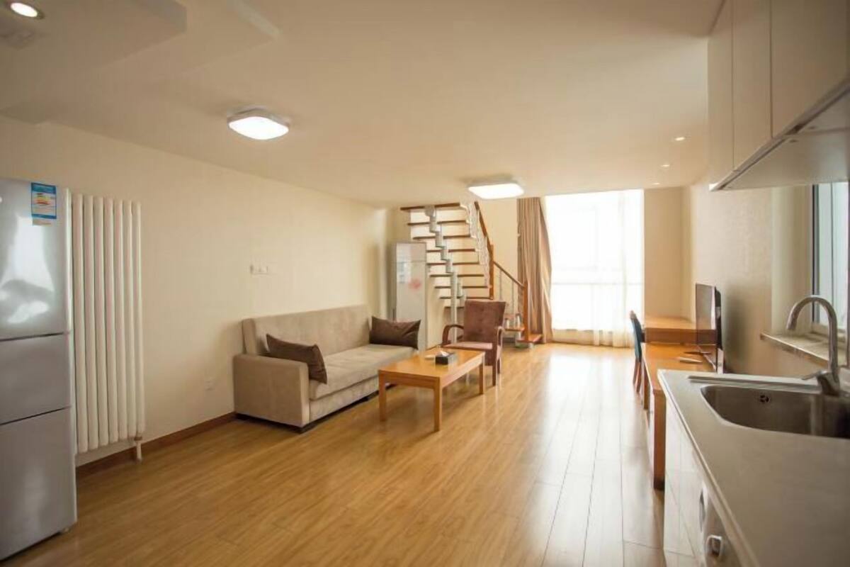A modern living room with a sofa, coffee table, and a staircase leading to another level.