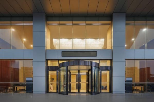 A modern building entrance with a revolving door, large windows, and a flat roof.