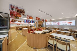 A restaurant interior with round tables, booths, and a counter area. - Wenhai International Hotel (Qingdao)