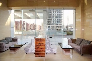 A modern lobby with glass walls, a central seating area, and a view of high-rise buildings. - Wenhai International Hotel (Qingdao)