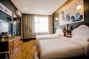 A hotel room with two beds, a desk, a television, and a large window with curtains.