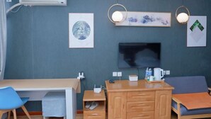 Une pièce comprenant un bureau, une chaise, un canapé, un téléviseur, des œuvres d’art et un meuble en bois.