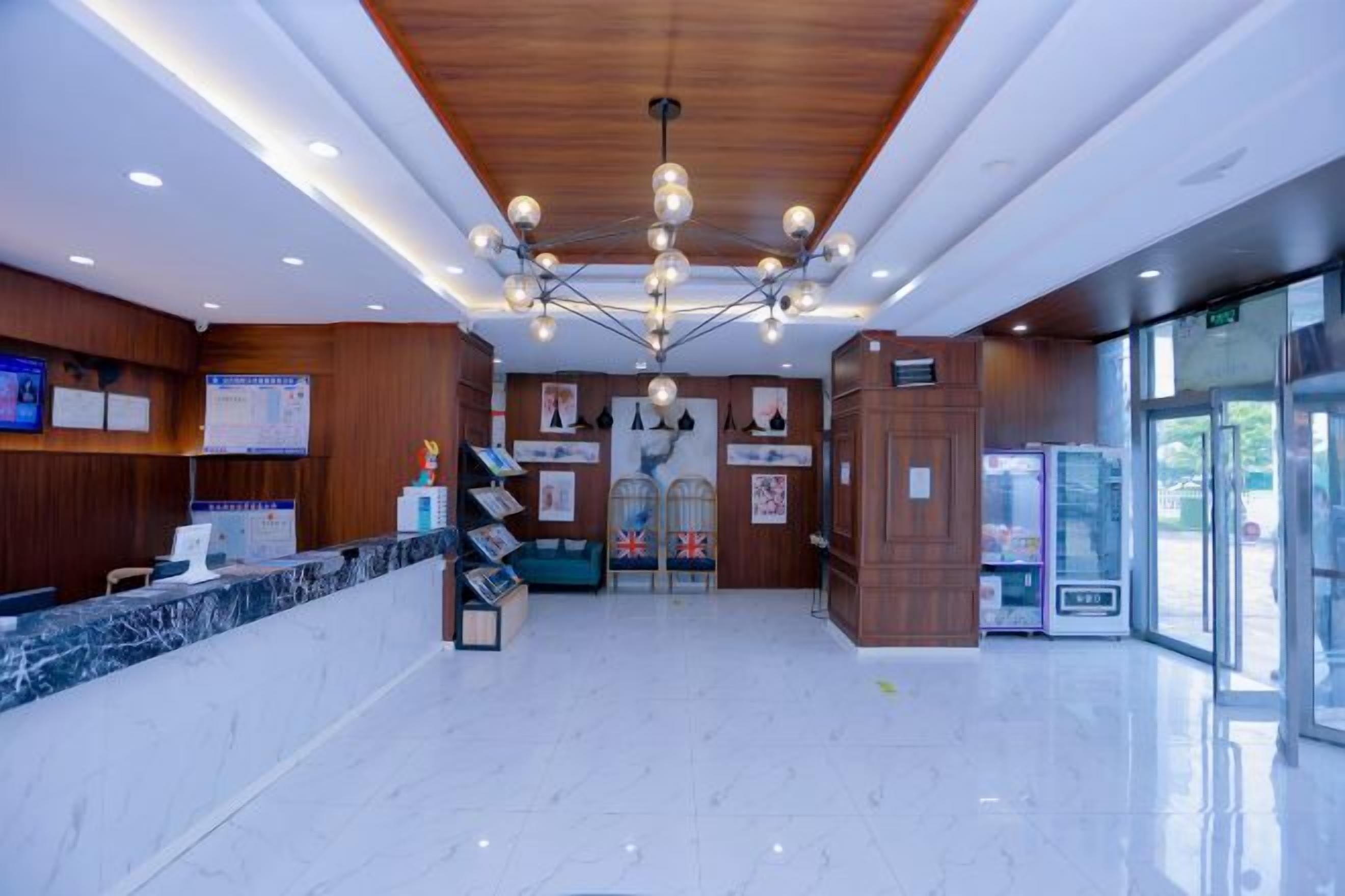 A hotel reception area with a marble counter, wooden paneling, and a chandelier.