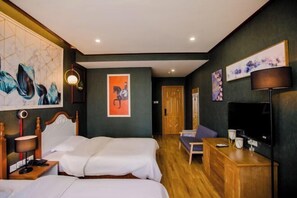 Una habitación de hotel con dos camas, un escritorio, un televisor y obras de arte en las paredes.