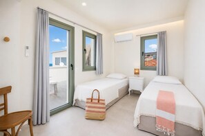 Habitación de hotel con dos camas, una silla, una mesita y vistas al exterior.