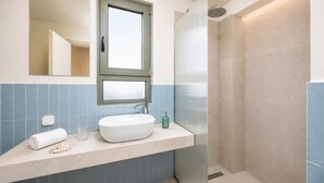 Ein Badezimmer mit großem Spiegel, Fenster, Waschbecken und Dusche.