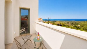 Ein Balkon mit Tisch, Stuhl und einer Weinflasche.