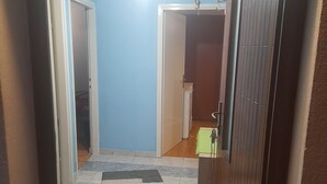 A hallway with a patterned rug, a wooden floor, and a blue wall. - Holiday Home Village Paradise - Holiday Home (Zemunik)
