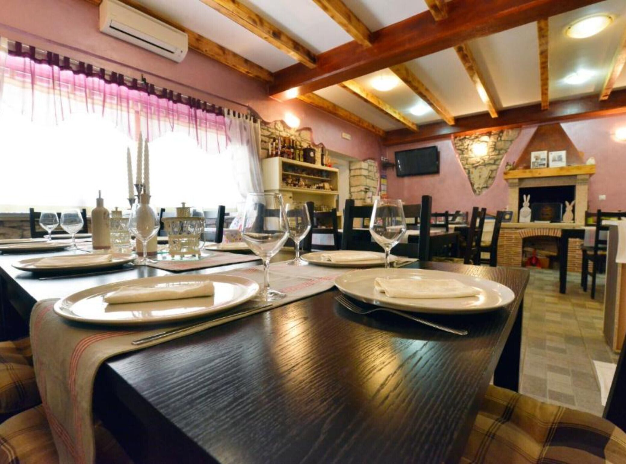 A dining area with wooden beams, a fireplace, and a stone wall.