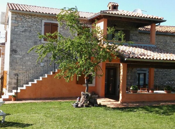 A two-story stone house with a tiled roof, a staircase leading to the upper floor, and a small tree in the front yard. - Authentic Istrian Rooms for Unforgettable Stays - Triple Room (Vodnjan)