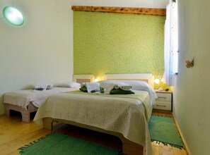 A room with two beds, a green wall, a wooden ceiling, and a small bedside table with a lamp. - Authentic Istrian Rooms for Unforgettable Stays - Triple Room (Vodnjan)
