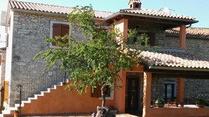 A two-story stone house with a tiled roof, a staircase leading to the upper floor, and a small tree in the front yard. - Authentic Istrian Rooms for Unforgettable Stays - Double Room (Vodnjan)