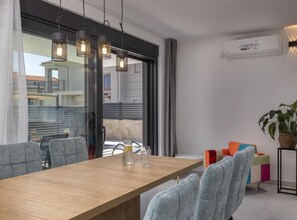 Un espace de salle à manger moderne avec une table en bois, des chaises à revêtement gris et des luminaires suspendus.
